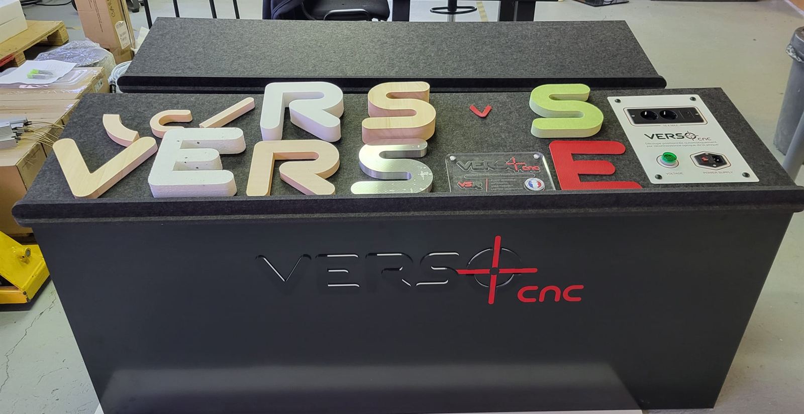 Présentoir VERSO CNC entièrement usiné sur VSR : caisson en Dibond plié, plateau en feutre acoustique, structure bois, logo en PMMA et vinyle, lettres en différentes matières